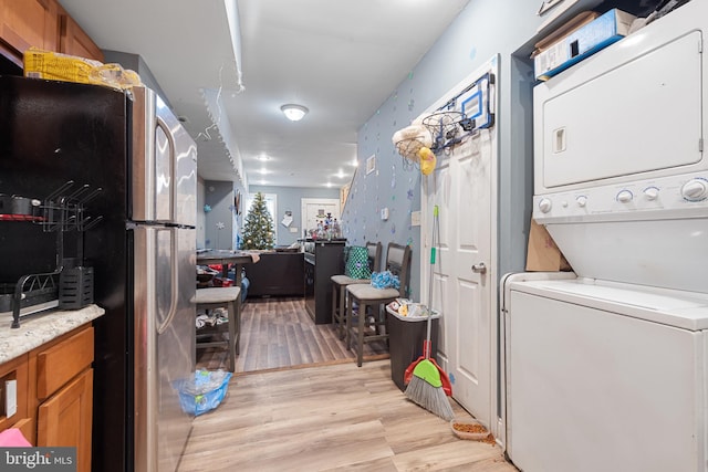 laundry room featuring light hardwood / wood-style floors and stacked washer and dryer