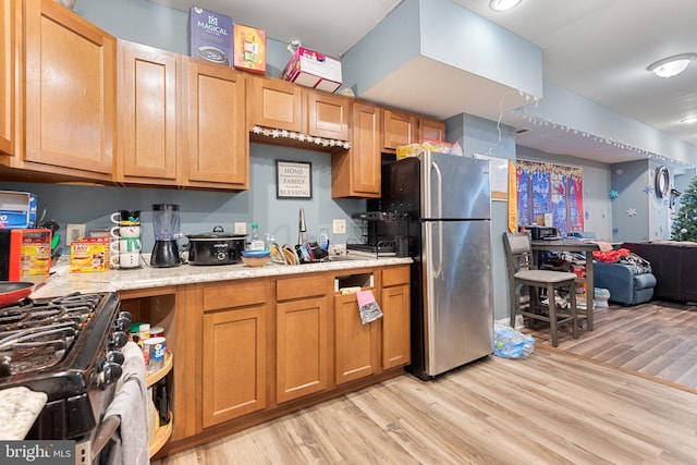 kitchen with stainless steel refrigerator, light hardwood / wood-style flooring, black range with gas cooktop, and sink