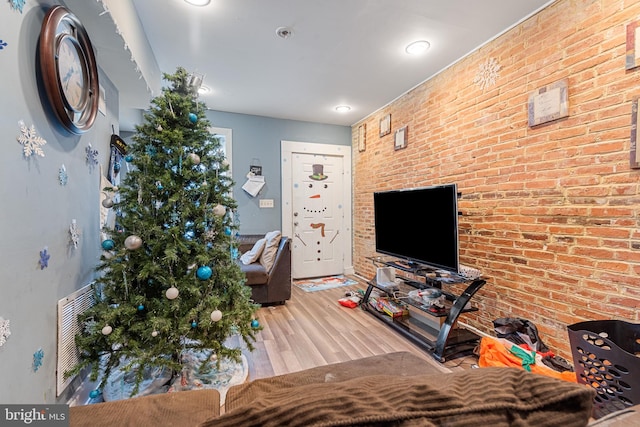 living room with light hardwood / wood-style floors and brick wall