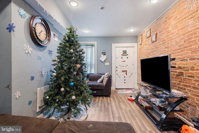 living room with hardwood / wood-style flooring and brick wall