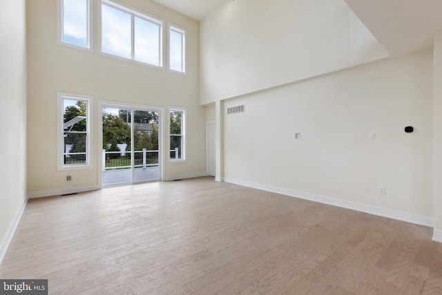 unfurnished living room featuring a towering ceiling and light wood-type flooring