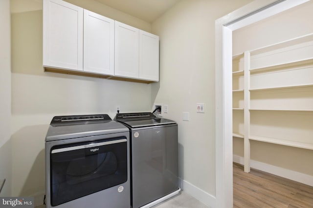 laundry room with washer and dryer, light hardwood / wood-style flooring, and cabinets