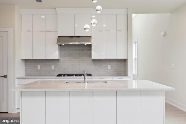 kitchen with a kitchen island with sink, light hardwood / wood-style flooring, white cabinets, and exhaust hood