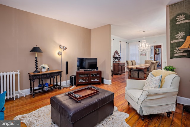 living room with wood-type flooring, ornamental molding, radiator, and a chandelier