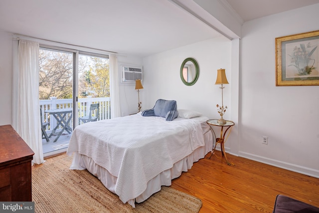 bedroom featuring access to outside, a wall unit AC, and light hardwood / wood-style flooring