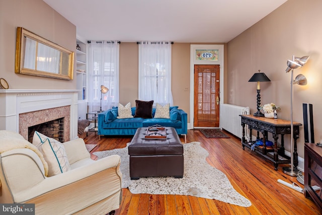 living room with wood-type flooring, radiator heating unit, and a premium fireplace