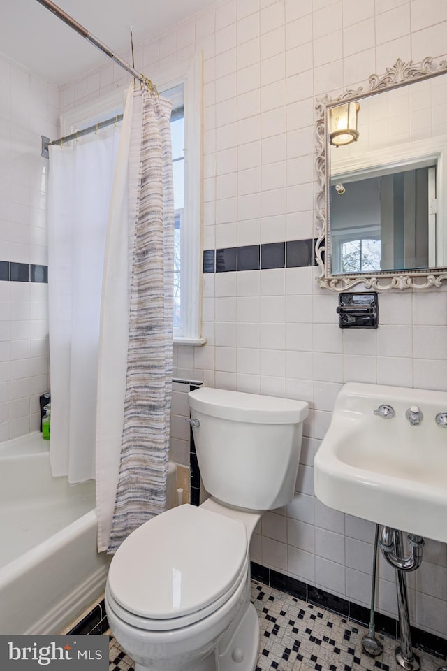 bathroom featuring toilet, shower / bathtub combination with curtain, plenty of natural light, and tile walls