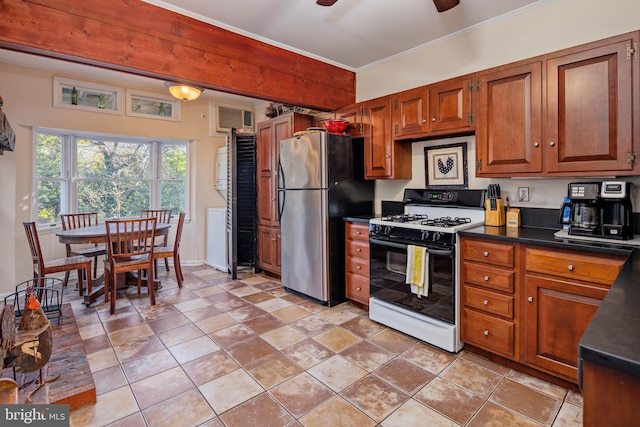 kitchen with stainless steel refrigerator, gas range gas stove, ceiling fan, crown molding, and light tile patterned flooring