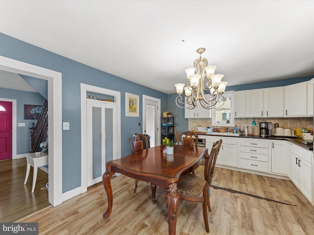 dining space with light hardwood / wood-style floors and a notable chandelier