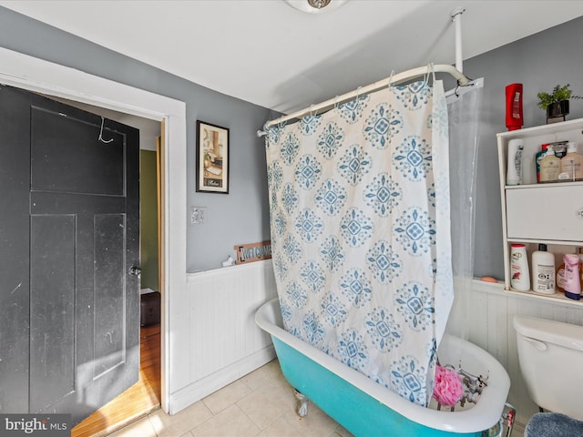 bathroom with wooden walls, toilet, and tile patterned flooring