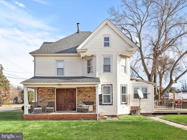 back of property with a wooden deck, a yard, and covered porch