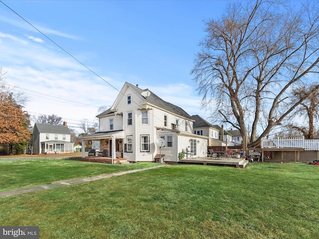 back of house with a deck and a lawn