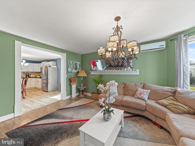 living room with an inviting chandelier, a wall unit AC, and light hardwood / wood-style flooring