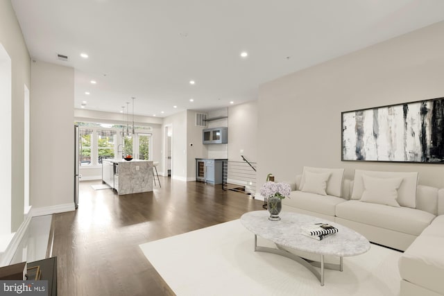 living room with dark hardwood / wood-style floors, sink, and beverage cooler