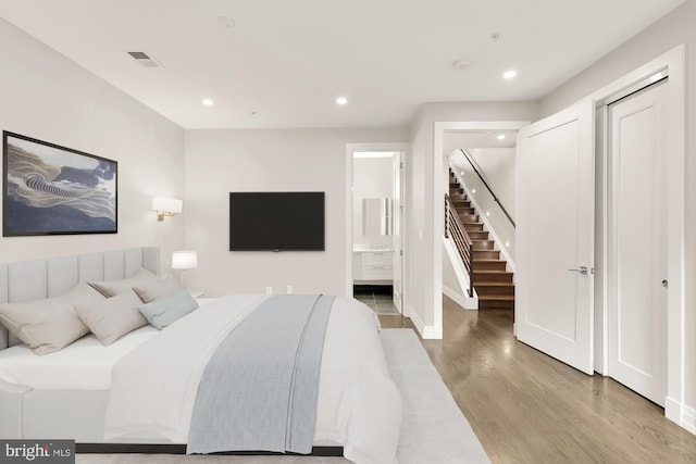 bedroom with hardwood / wood-style floors and ensuite bath