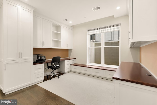 office with dark hardwood / wood-style flooring and built in desk