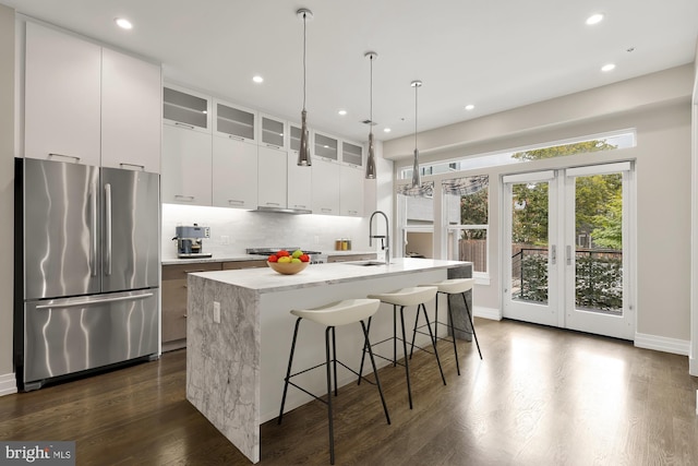 kitchen featuring dark hardwood / wood-style flooring, white cabinetry, a center island with sink, and appliances with stainless steel finishes