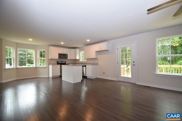 kitchen featuring white cabinets, appliances with stainless steel finishes, dark hardwood / wood-style flooring, and a kitchen island