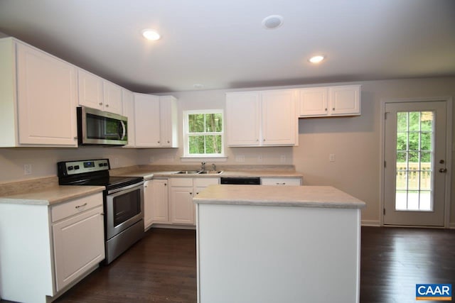 kitchen featuring white cabinetry, sink, stainless steel appliances, dark hardwood / wood-style floors, and a kitchen island