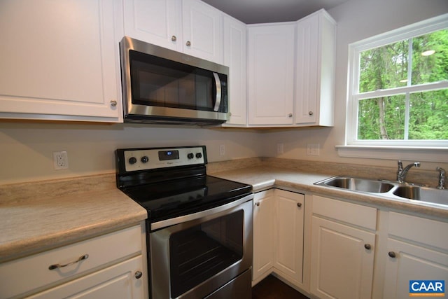 kitchen featuring stainless steel appliances, white cabinetry, and sink