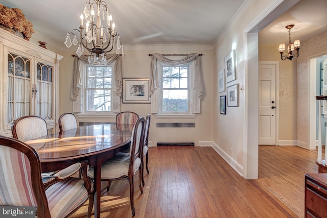 dining area with hardwood / wood-style flooring, ornamental molding, radiator, and an inviting chandelier