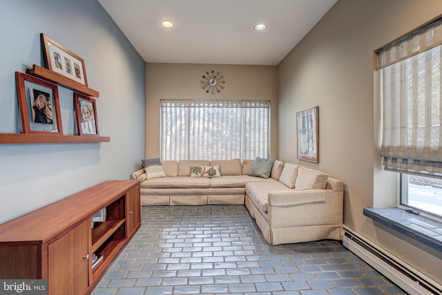 living room with a baseboard heating unit and a wealth of natural light