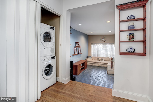 washroom with stacked washing maching and dryer and light hardwood / wood-style floors