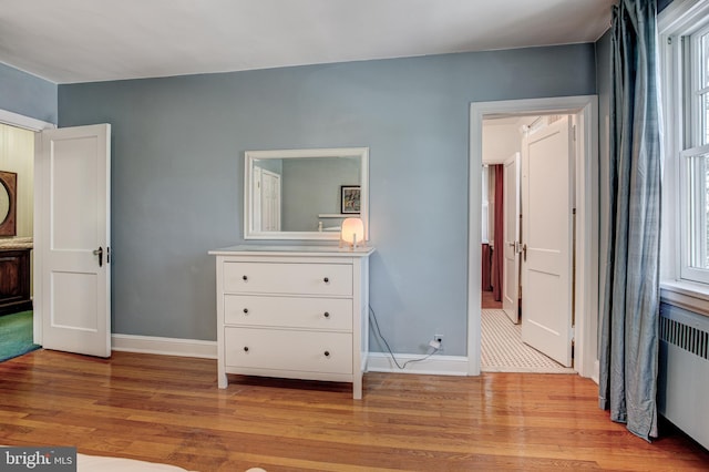 bedroom with radiator heating unit and light hardwood / wood-style flooring