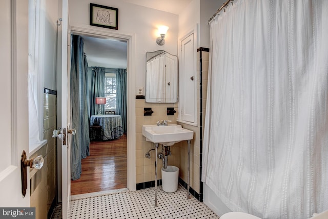 bathroom with tile walls, sink, and shower / tub combo with curtain