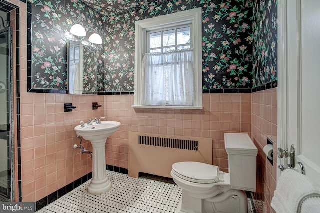 bathroom with tile patterned floors, radiator heating unit, toilet, and tile walls