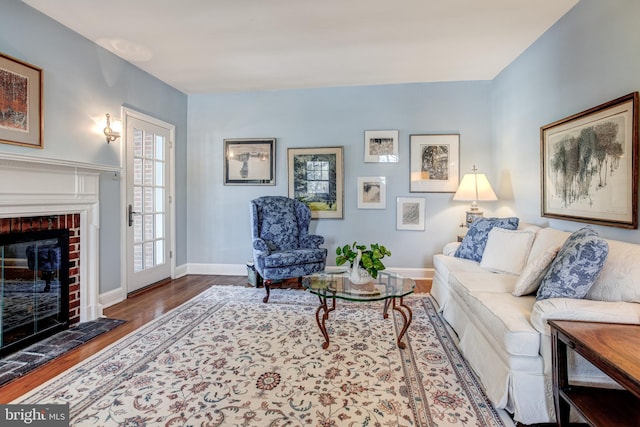 living room featuring a brick fireplace and wood-type flooring