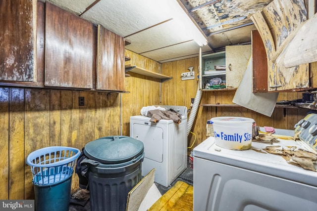 clothes washing area featuring cabinets, separate washer and dryer, and wooden walls