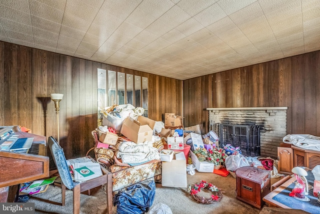 interior space with wood walls, carpet floors, and a brick fireplace