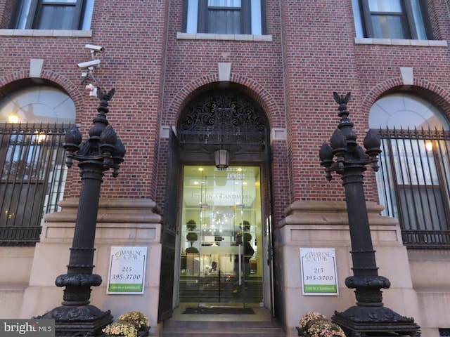 property entrance with fence and brick siding