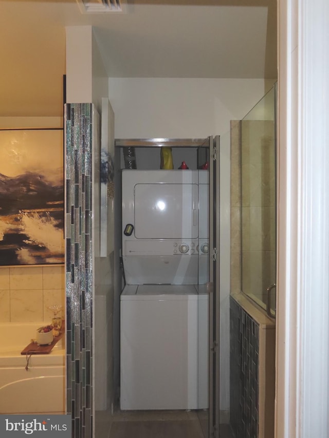 bathroom with a tub and stacked washer and clothes dryer