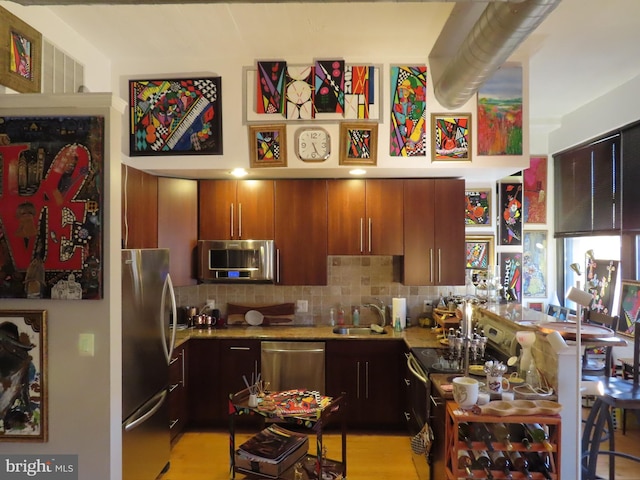 kitchen with decorative backsplash, sink, light hardwood / wood-style flooring, and appliances with stainless steel finishes