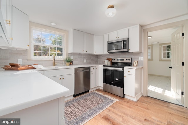 kitchen with sink, white cabinets, stainless steel appliances, and light hardwood / wood-style floors