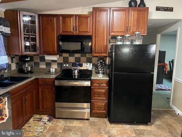 kitchen with decorative backsplash, sink, light stone countertops, and black appliances