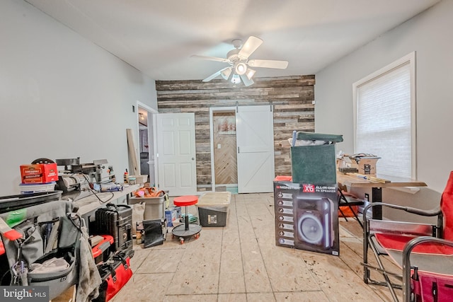 interior space featuring ceiling fan and wooden walls