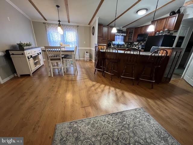 kitchen with a kitchen breakfast bar, dark hardwood / wood-style flooring, and ornamental molding