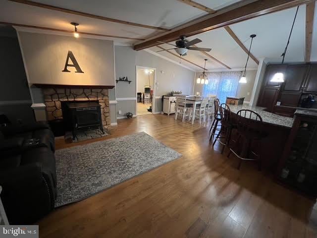 living room featuring a fireplace, hardwood / wood-style floors, lofted ceiling with beams, and ceiling fan