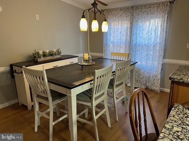 dining space with wood-type flooring, crown molding, and a chandelier