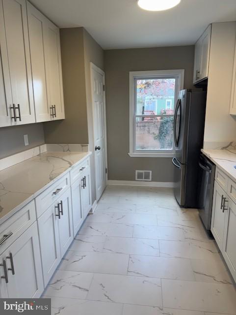 kitchen with light stone countertops, white cabinetry, and stainless steel appliances