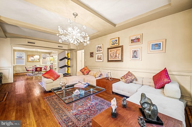 living area with a decorative wall, visible vents, an inviting chandelier, and hardwood / wood-style floors