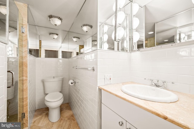 full bath with tile patterned floors, toilet, tile walls, a shower stall, and vanity