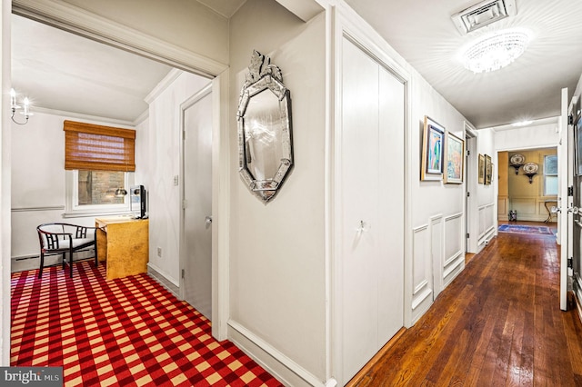 corridor featuring dark wood-type flooring, a baseboard heating unit, and ornamental molding