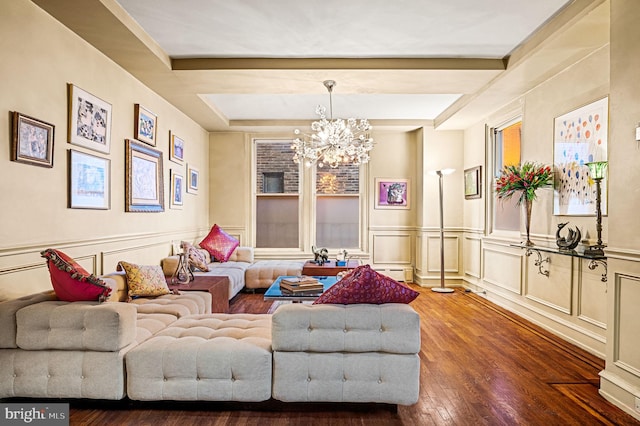 living room featuring hardwood / wood-style floors, an inviting chandelier, a decorative wall, and a wainscoted wall