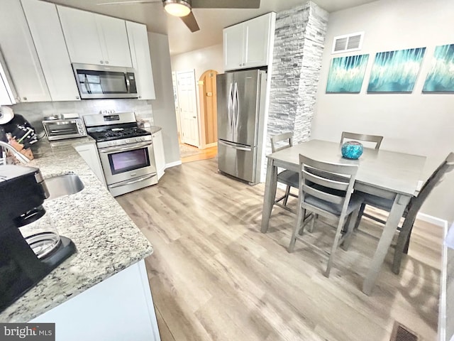 kitchen with light hardwood / wood-style flooring, ceiling fan, light stone counters, white cabinetry, and stainless steel appliances