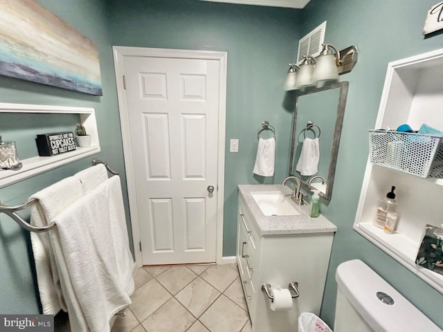 bathroom with toilet, vanity, and tile patterned floors