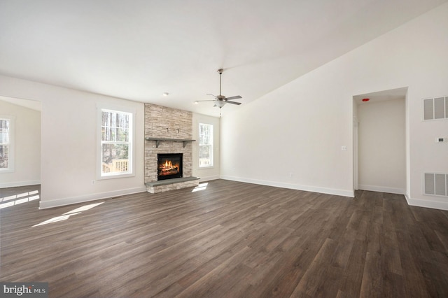 unfurnished living room featuring ceiling fan, dark hardwood / wood-style flooring, lofted ceiling, and a stone fireplace